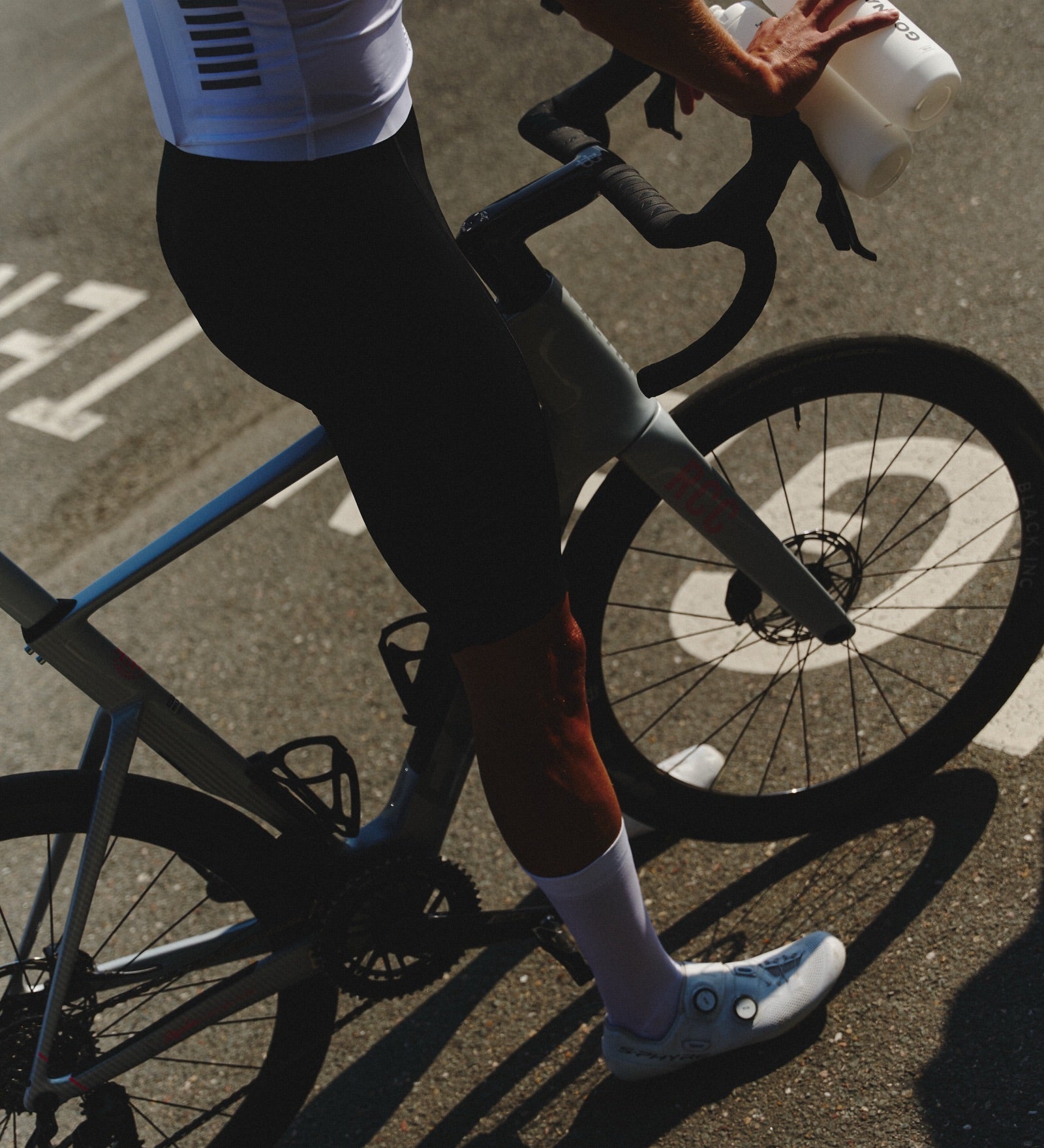 Cyclist holding a GONNA bottle, carbohydrate drink mix on the road