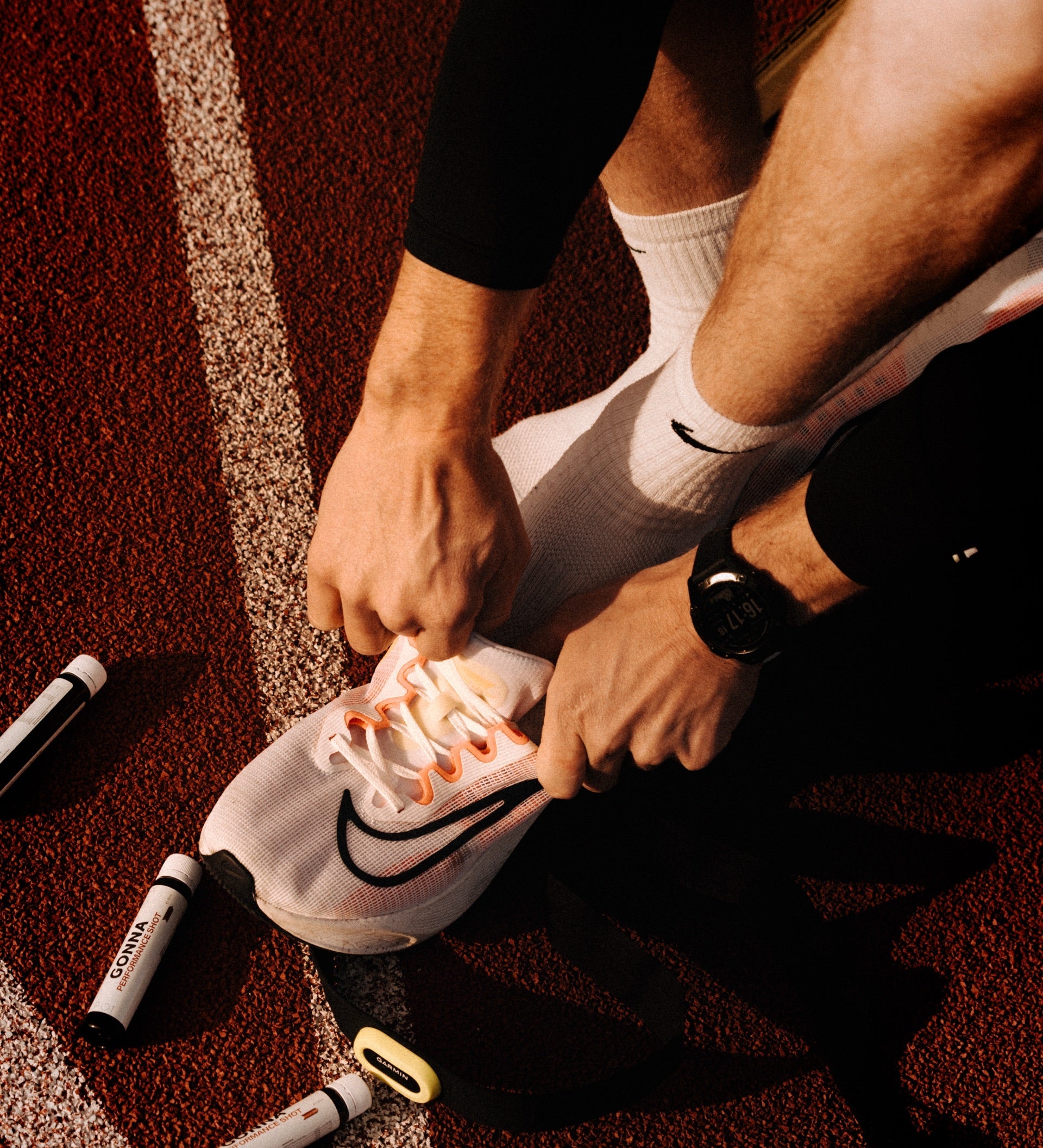 Runner lacing spikes on the track beside GONNA fuel