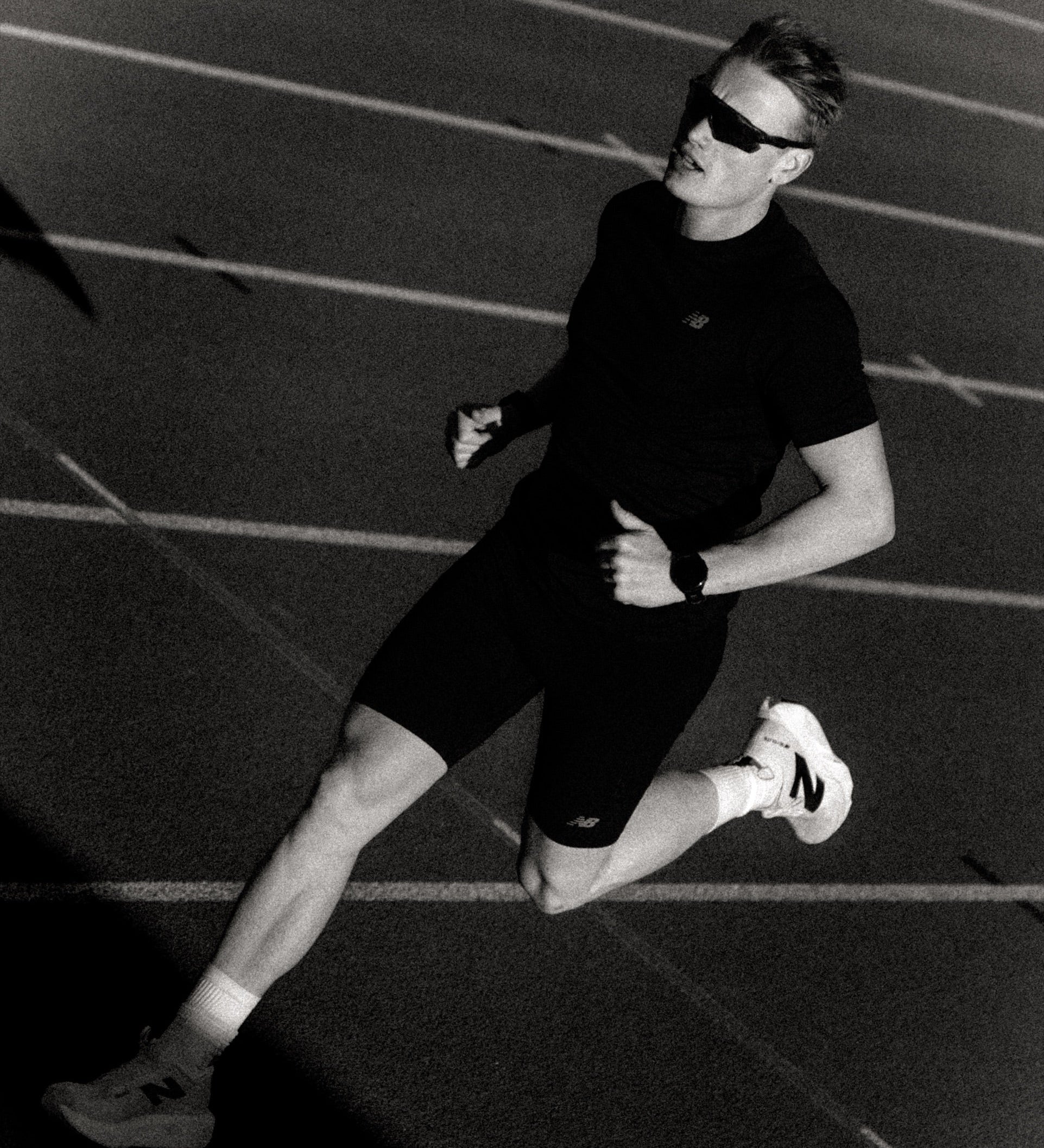 Runner mid-stride on an athletics track, black and white